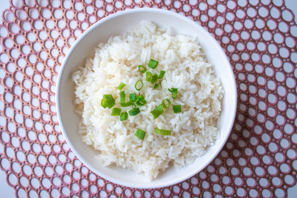 Bengali Recipes: A bowl of cooked white rice garnished with green onions, perfect for culinary presentations.