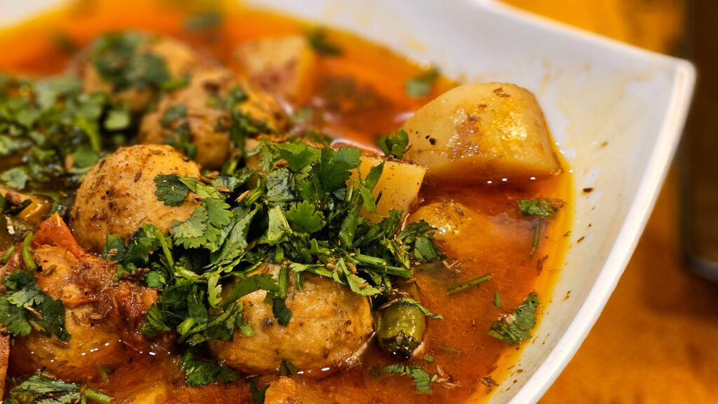Indian Recipes: Close-up of a flavorful Indian aloo kofta curry garnished with fresh coriander.